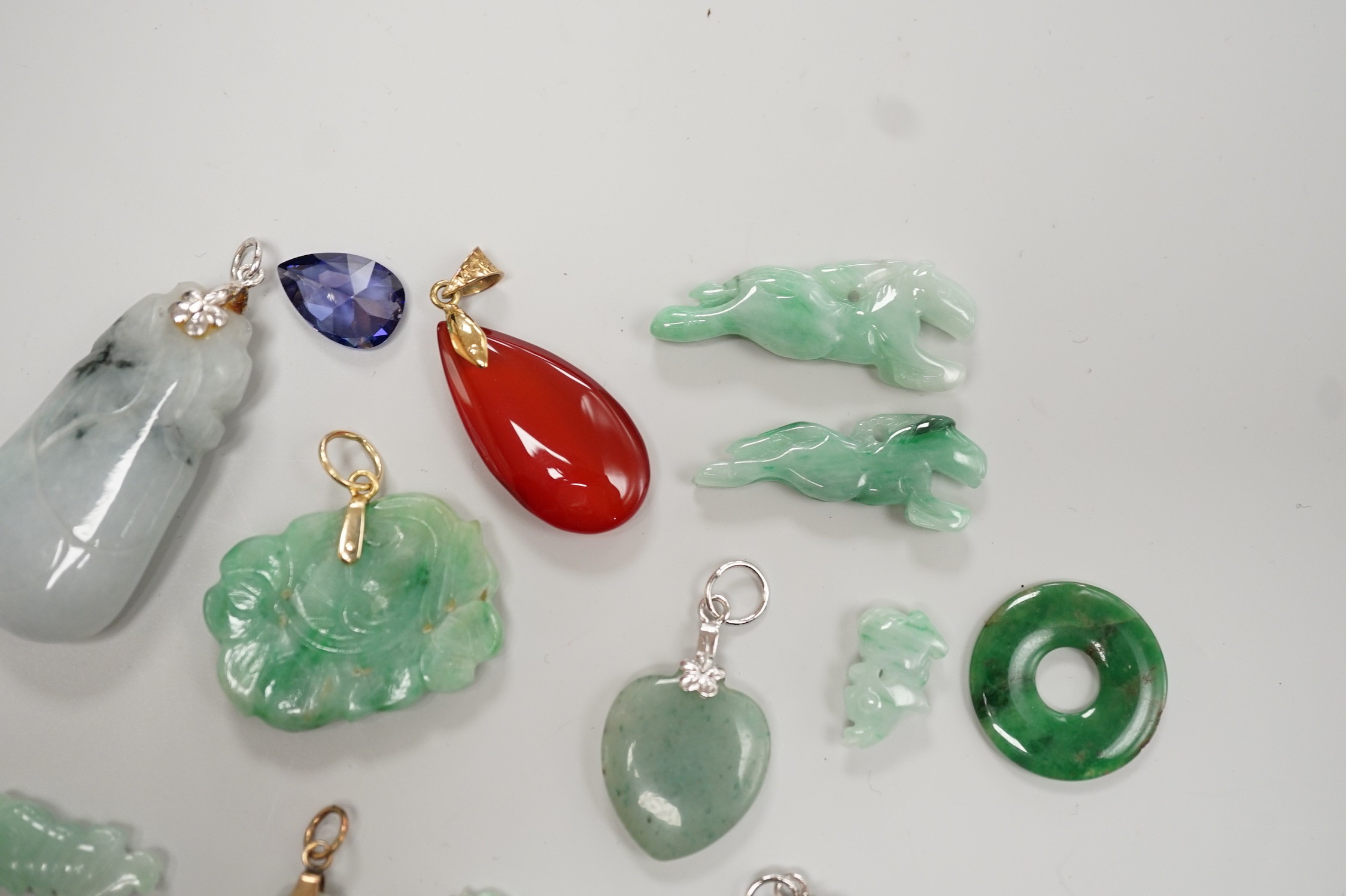 Twelve assorted carved jadeite items including five pendants, largest 40mm, a 14k mounted carnelian pendant and an unmounted pear cut simulated Tanzanite.